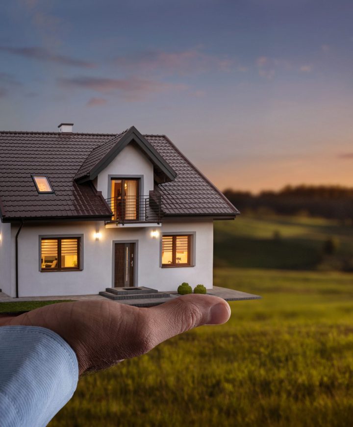 Concept of buying or building new home. Male hand showing, offer Concept of buying or building new home. Male hand showing, offering a new dream house at the empty field with copy space